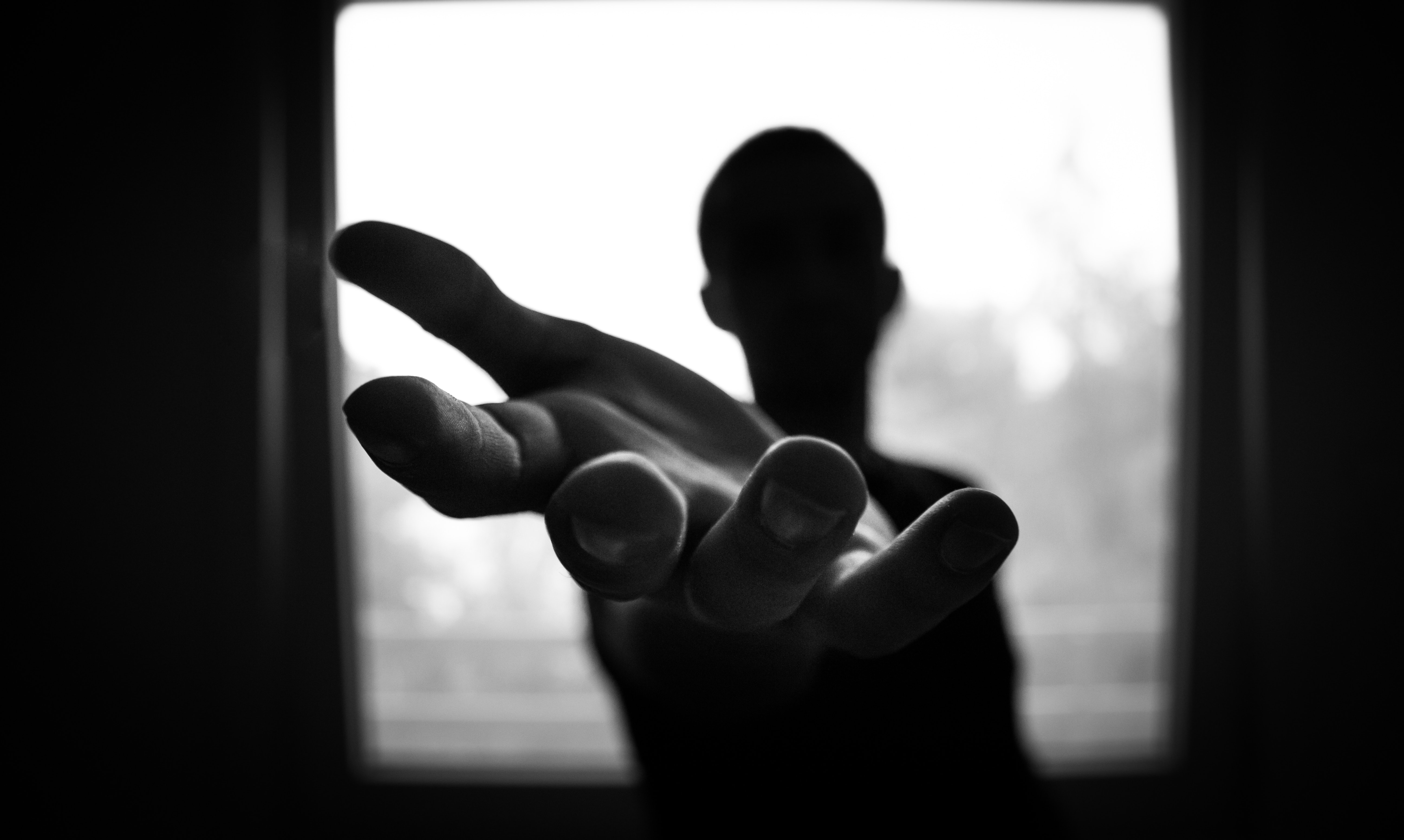 silhouette of person reaching out hand
